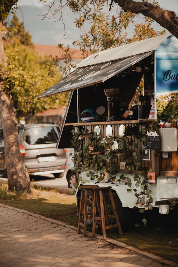 A cozy outdoor food stand surrounded by greenery on a vibrant sunny street.